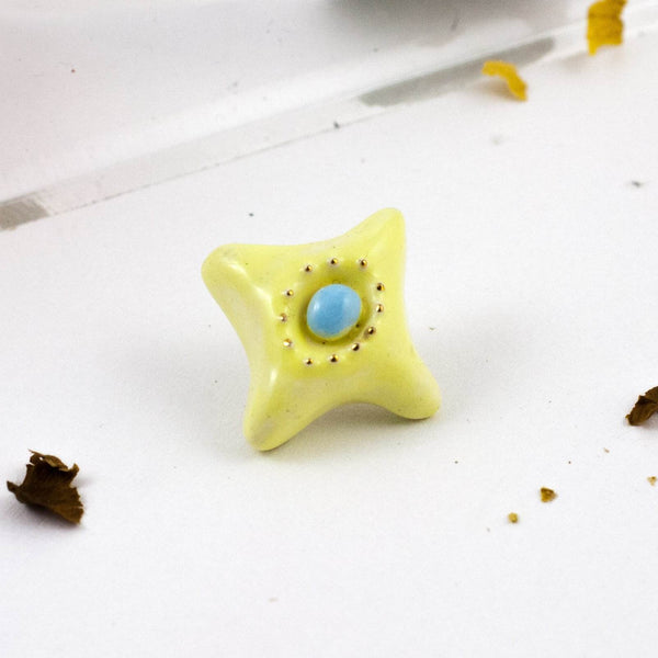 yellow brooch with blue center and gold details