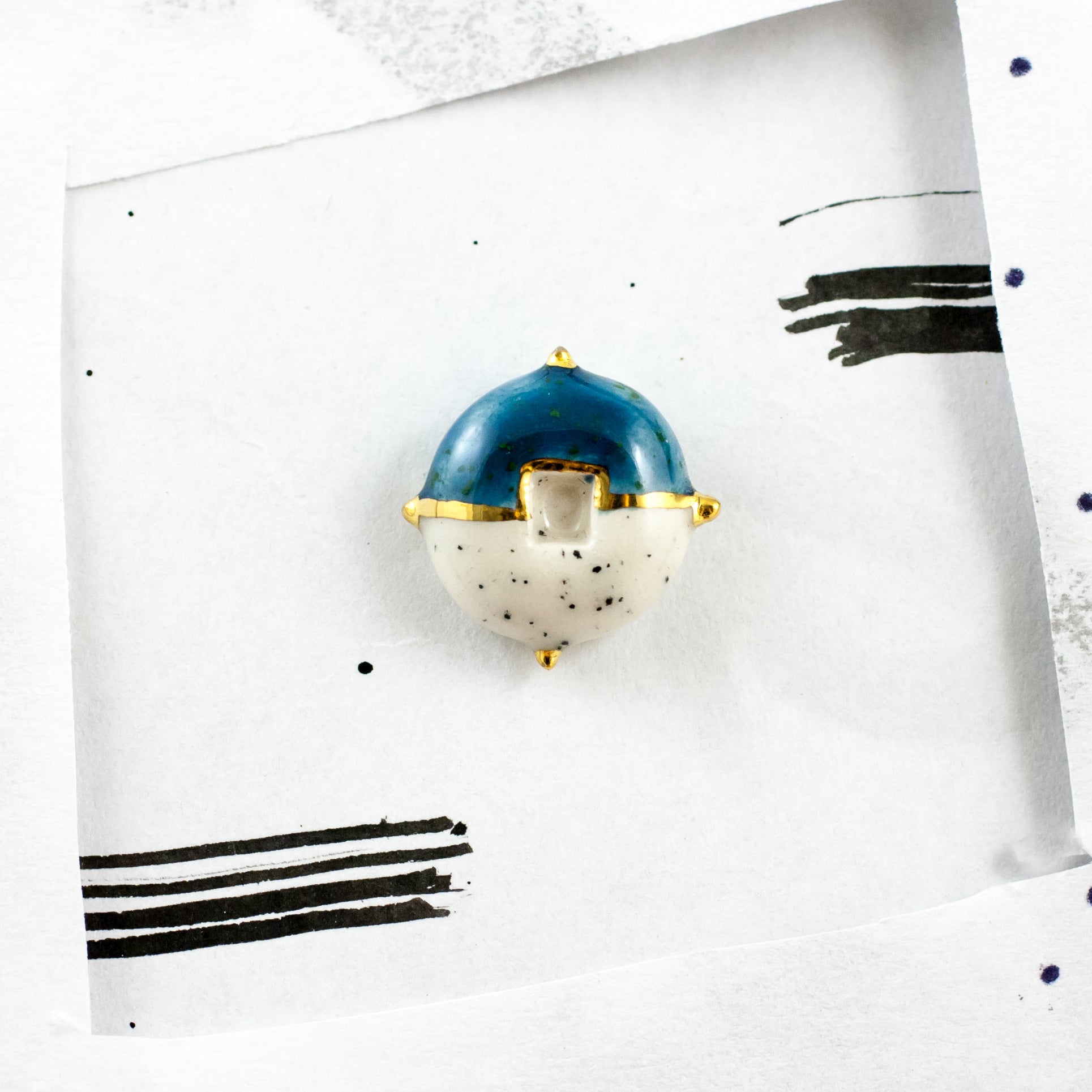 Zila un balta keramikas broša ar zelta spīduma dekoru