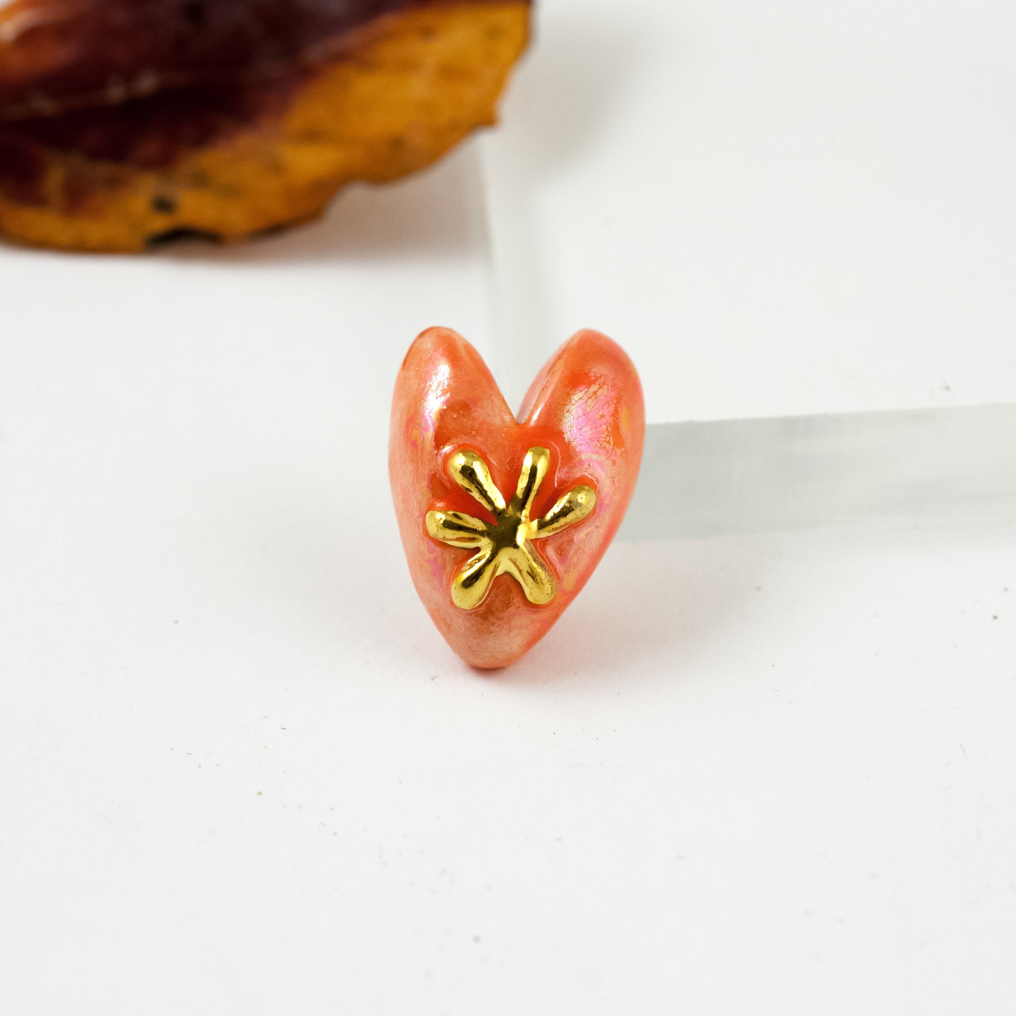 Oranžinės spalvos sagė su auksine gėle