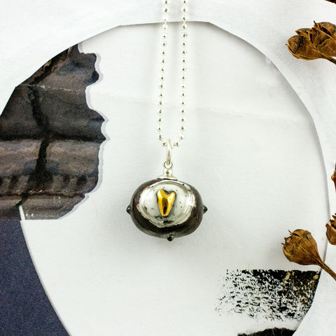 Black oval ceramic pendant with a golden heart