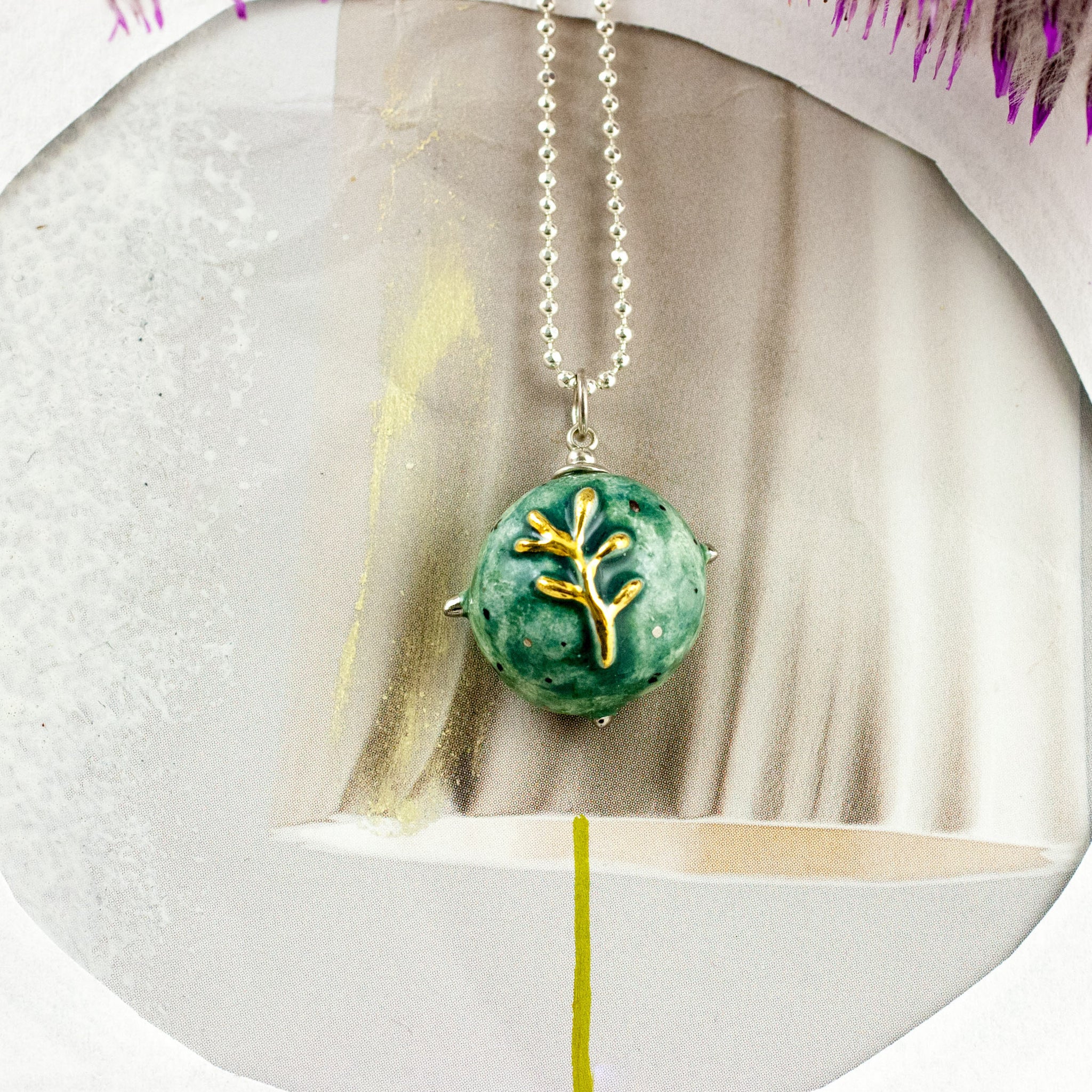 Teal round pendant with a golden flower