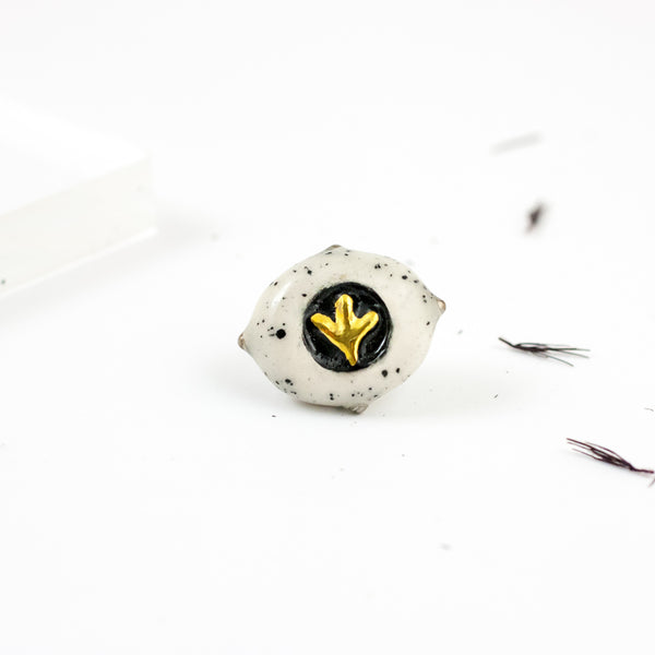 White speckled brooch with a golden flower