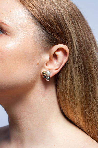 Mismatched silver stud earrings with a pearl and ceramic details