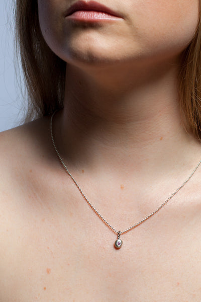 A tiny silver pendant with a pink zircon