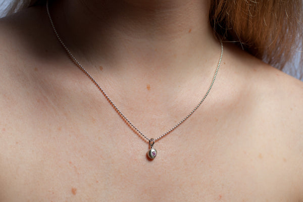 A tiny silver pendant with a pink zircon
