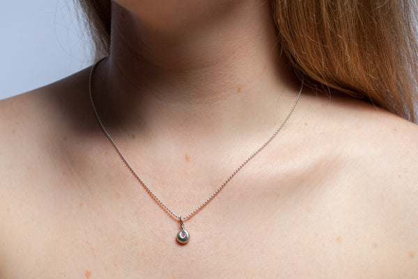 A silver pendant with a pink zircon
