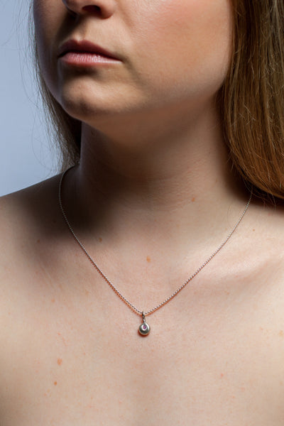 A silver pendant with a pink zircon