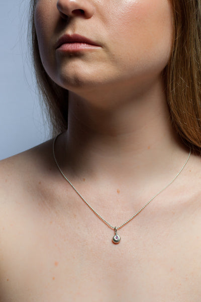 A silver pendant with a pink zircon
