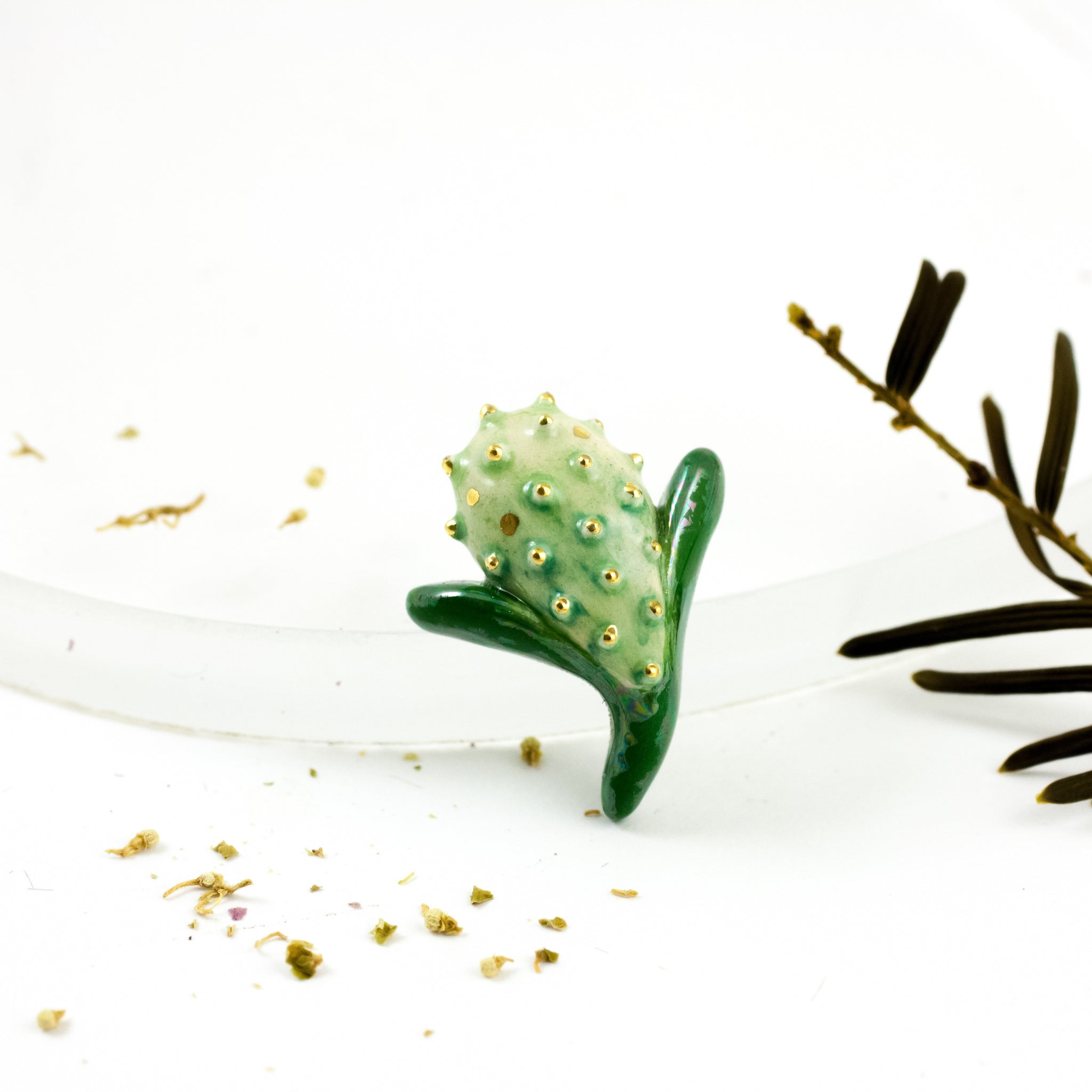 Žalia sagė su perlų blizgesiu ir aukso liustro dėmelėmis