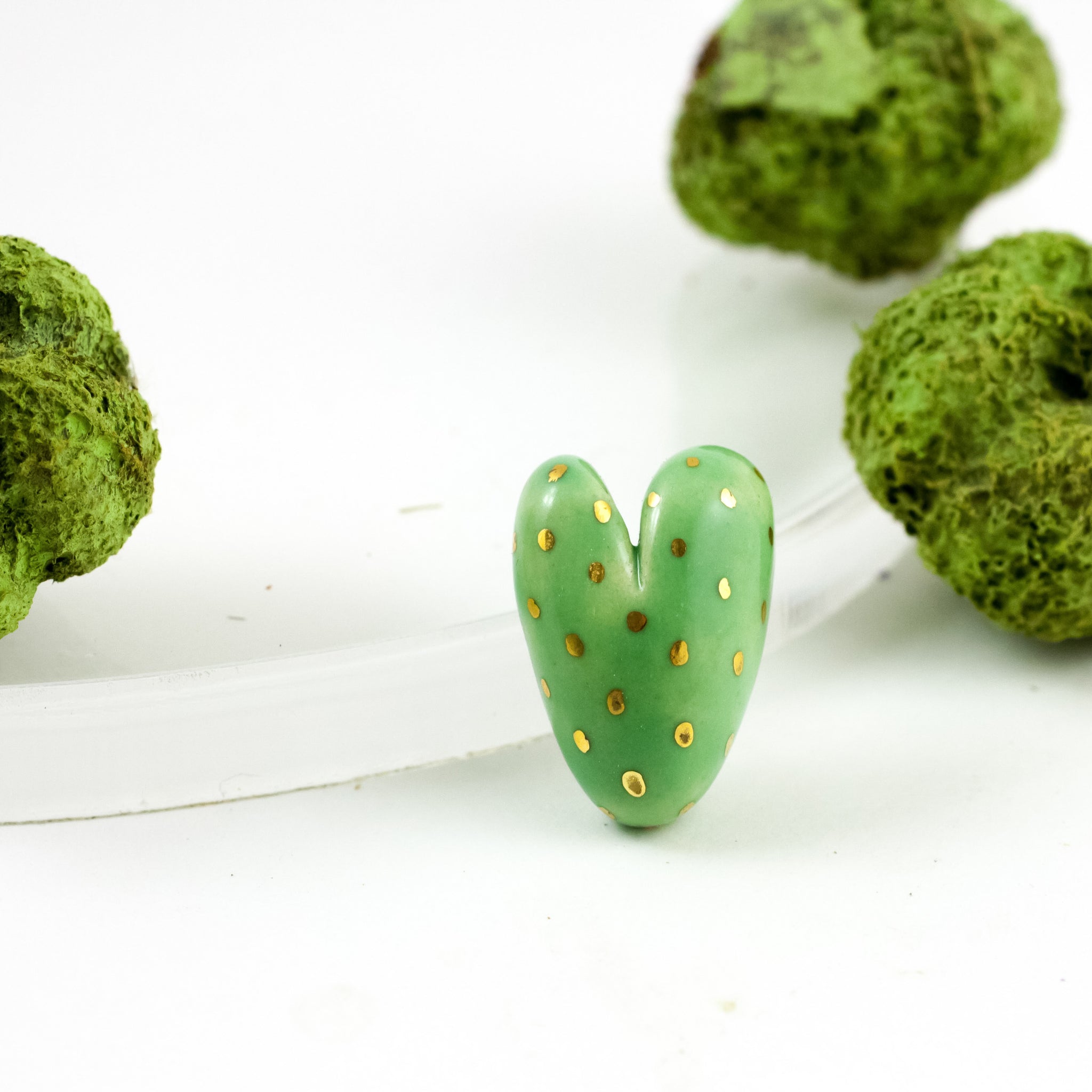 Ryškiai žalia širdelės formos sagė su aukso blizgesio dekoru